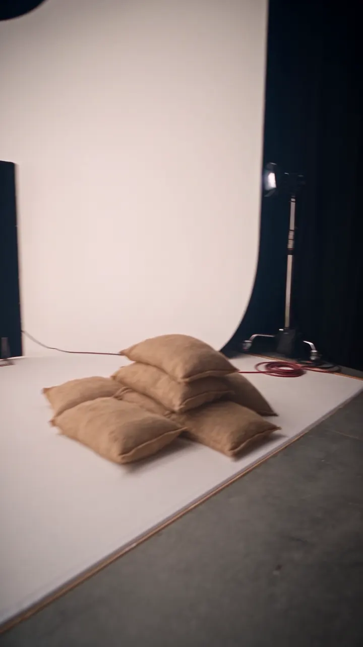 The studio's empty white cyclorama: sandbags, a black flag and a light on a stand.